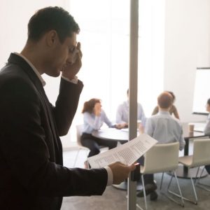 Nervous stressed sweaty businessman speaker wiping sweat feel anxious afraid stuttering before speech reading preparing practicing standing at office meeting door, public speaking fear phobia concept